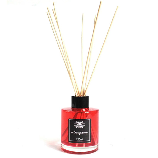 Difusor aromático de 120ml con líquido rojo, frasco de vidrio cilíndrico, tapón negro y varillas de madera clara.