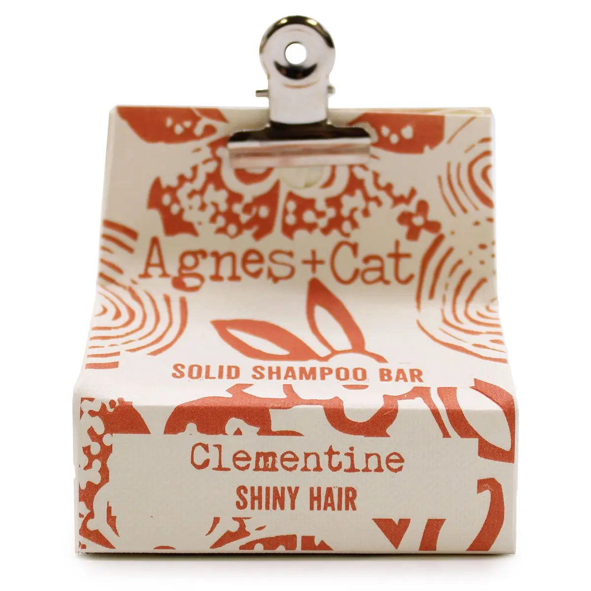 Champú sólido Clementina Agnes + Cat en caja de papel crema con estampado naranja y pinza metálica superior.