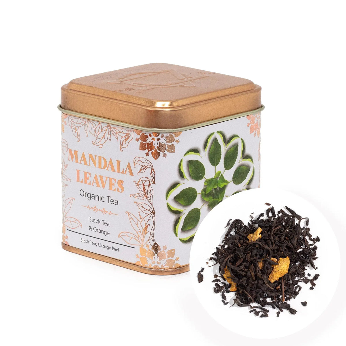 Lata cuadrada dorada con diseño floral y muestra de té negro con trozos de naranja sobre fondo blanco.