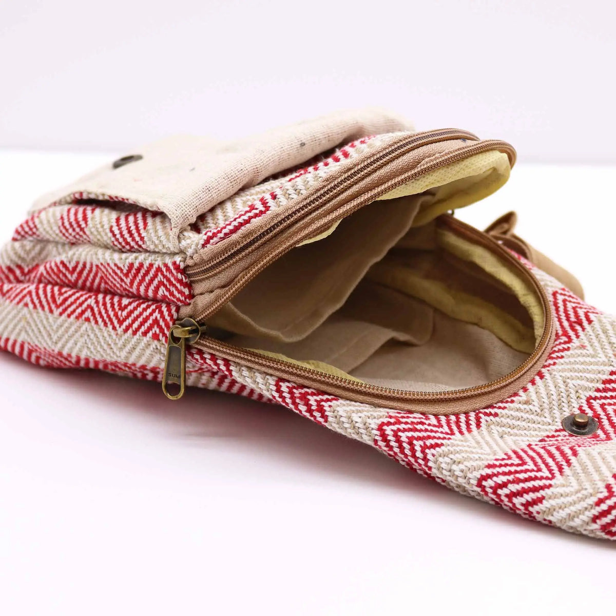 Bolso bandolera de algodón con patrón en zigzag rojo y beige, cierre de cremallera y solapa con broche.