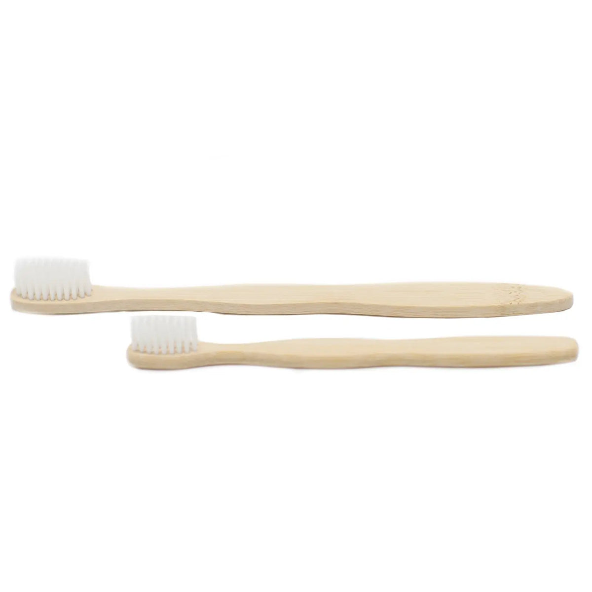 Dos cepillos de dientes de bambú con cerdas blancas, uno grande y otro pequeño, sobre fondo blanco.