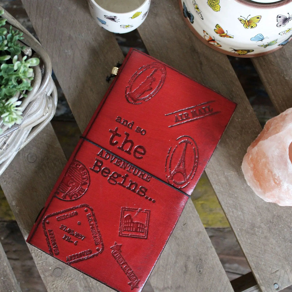 Cuaderno de viaje de cuero rojo con estampados de sellos, "And to the adventure begins...". Ideal para exploradores.