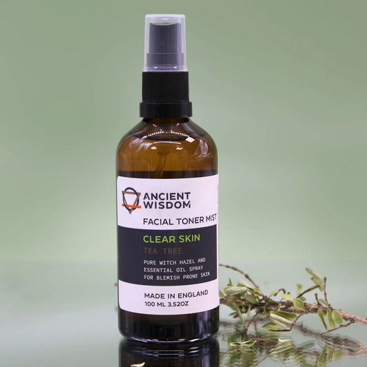 Frasco de vidrio ámbar de 100ml con atomizador negro, etiqueta blanca y texto, sobre fondo verde claro con una rama.