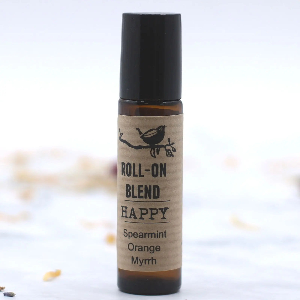Aceite esencial roll-on Happy de menta, naranja y mirra, en frasco marrón con tapa negra.