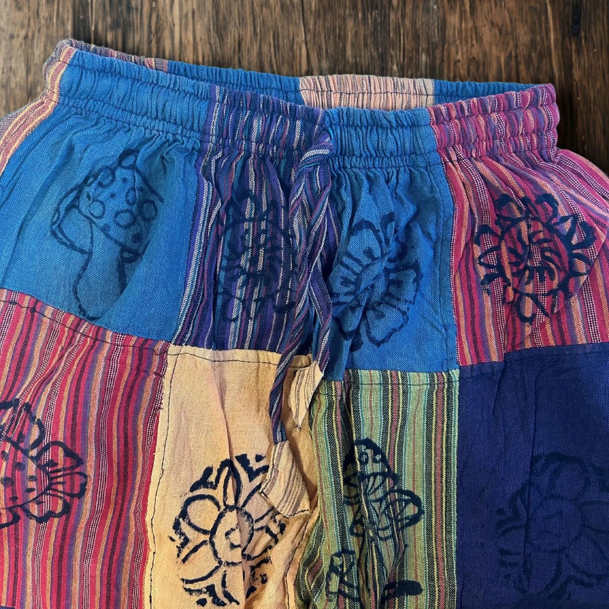 Pantalón tipo sari con parches de colores, estampado de hongos y flores en bloques, cintura elástica y cordón.
