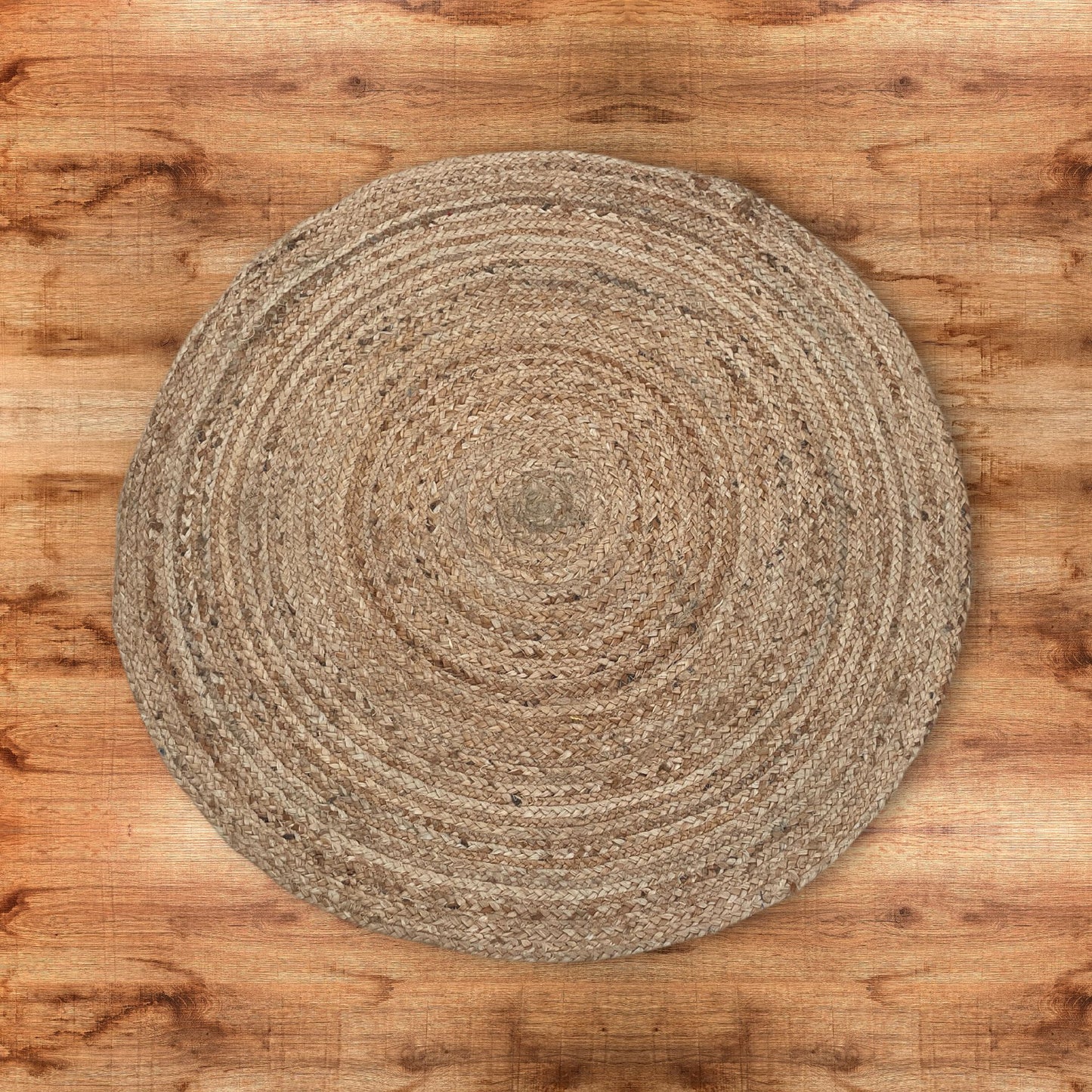 Alfombra redonda de 90 cm tejida en yute natural con fibras trenzadas, sobre un suelo de madera. Estilo rústico.
