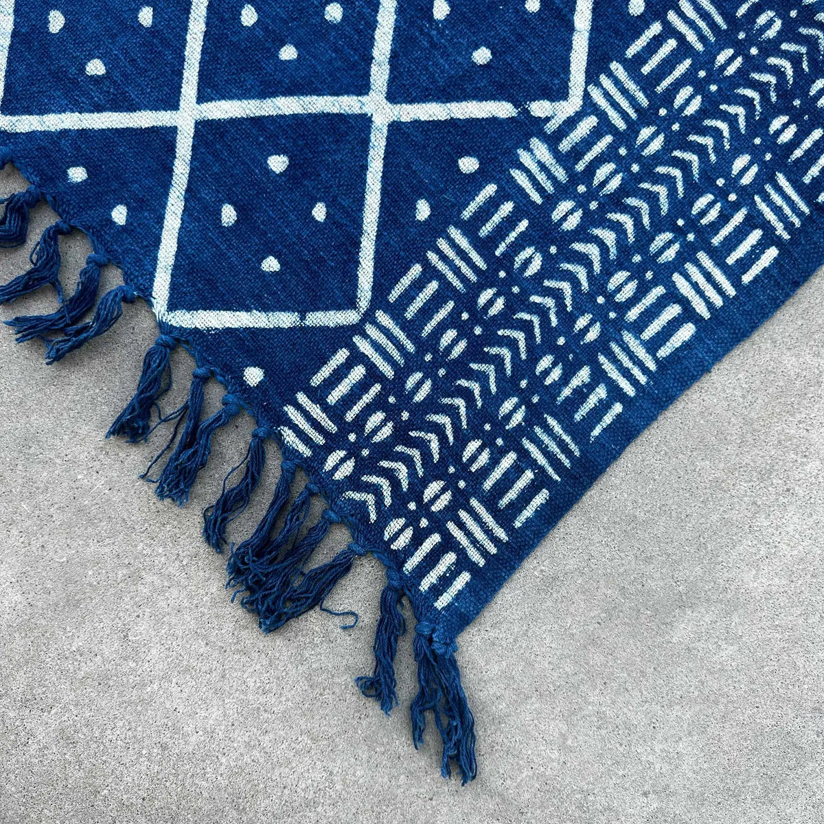 Alfombra azul con patrones en blanco, tejido de algodón, estilo moderno, con flecos decorativos.