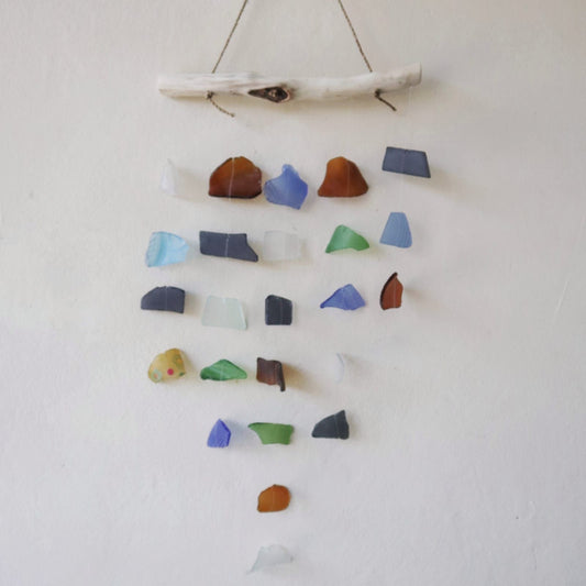 Carillón decorativo de 5 cuerdas con fragmentos de vidrio reciclado de colores sobre una rama de madera clara.