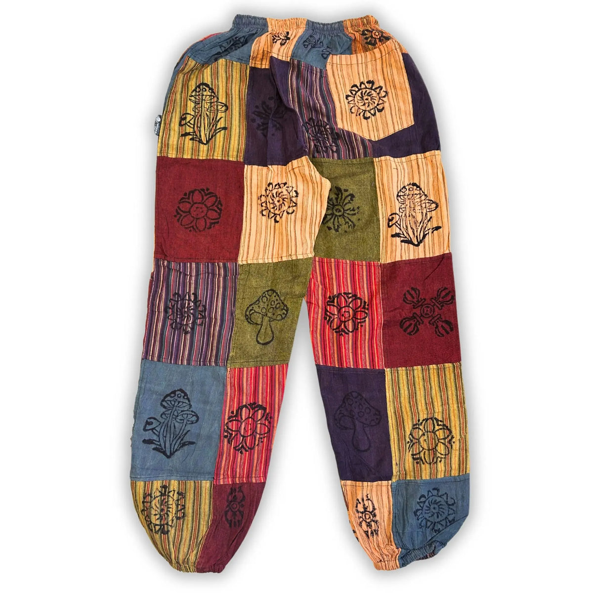 Pantalón tipo bombacho de parches con estampados de hongos y flores en tonos naranja, terracota, azul y verde.