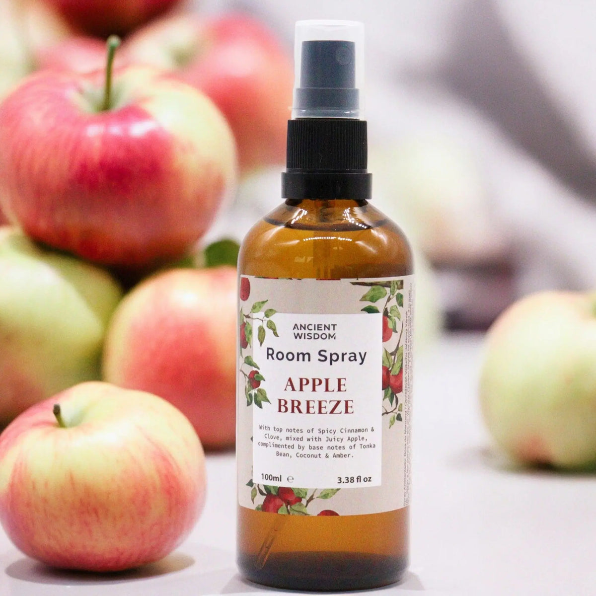 Spray de 100 ml en frasco ámbar con etiqueta de manzanas, rodeado de manzanas frescas sobre una superficie clara.