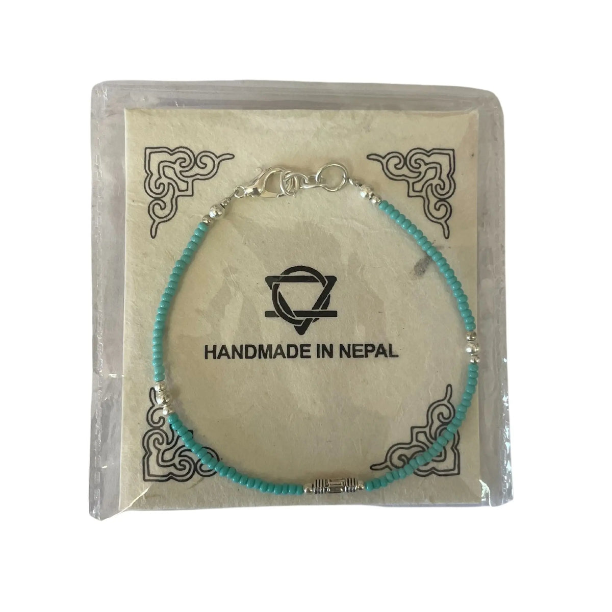 Pulsera artesanal de Nepal, cuentas turquesas y separadores plateados, presentada en empaque decorativo.
