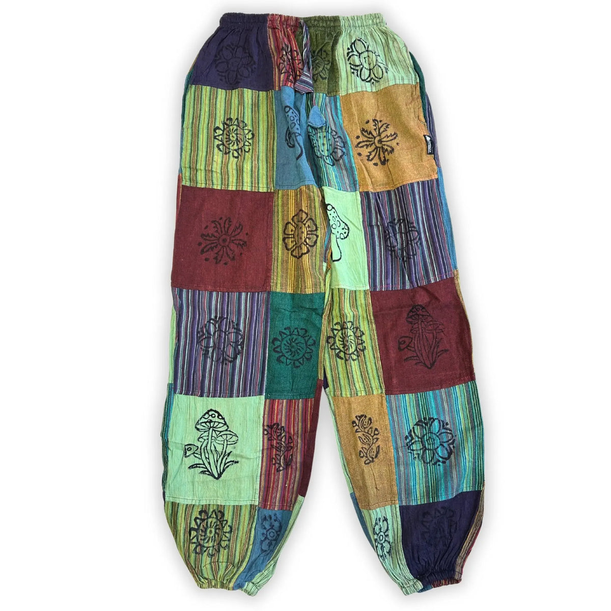 Pantalón estilo hippie de retazos en tonos verdes y tierra, con estampado de hongos y flores, cintura y tobillos elásticos.