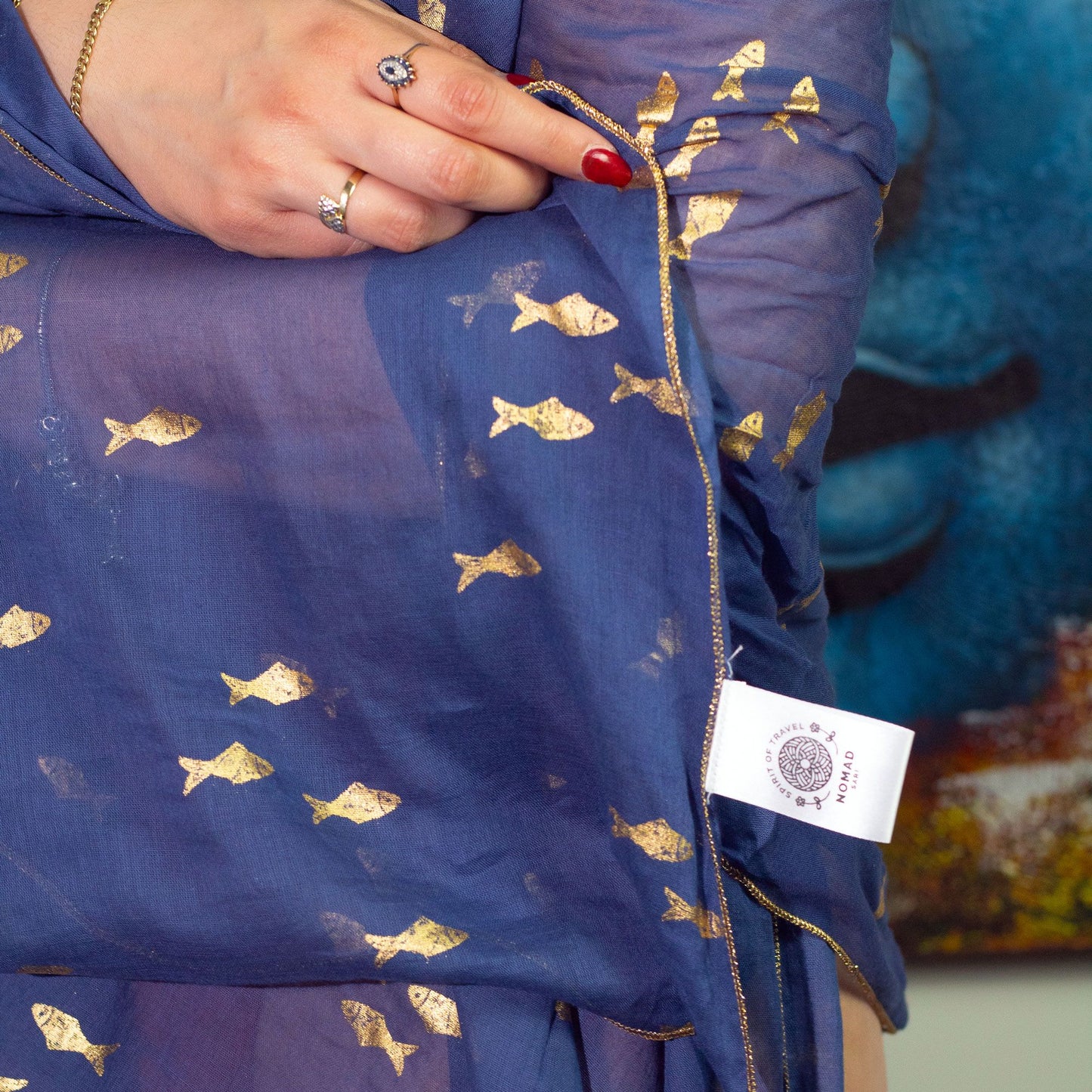 Pareo de tela azul semitransparente con estampado de peces dorados y borde con detalle metálico fino.