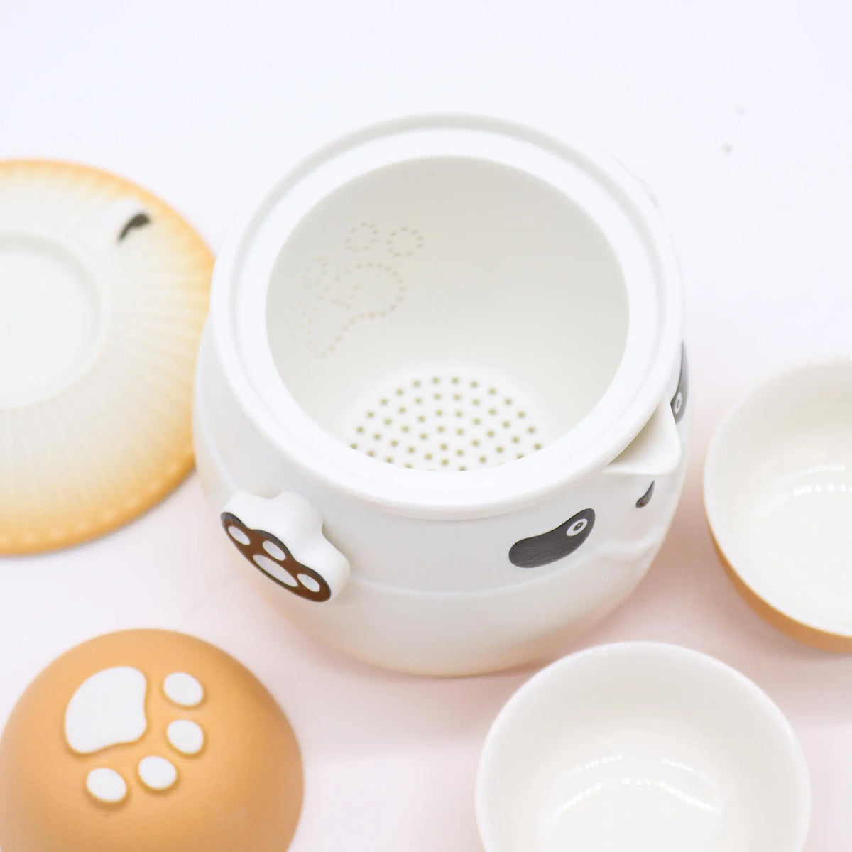 Juego de té de cerámica con diseño de panda y huellas, incluye tetera con filtro y tazas en tonos blanco y naranja suave