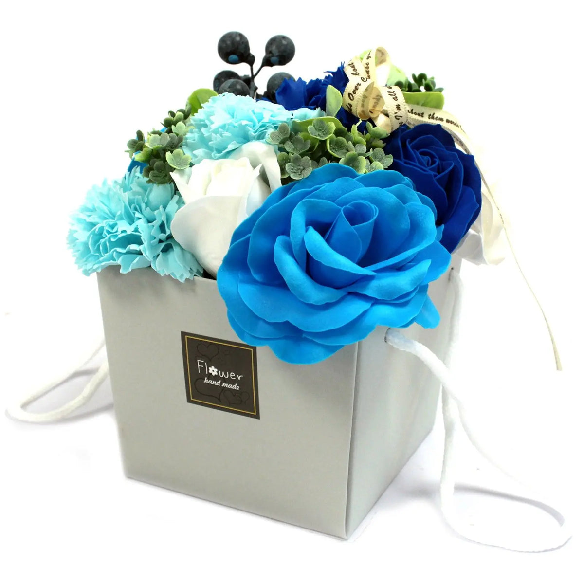 Bouquet de rosas y claveles de jabón en tonos azules y blancos, presentado en una caja gris con asa blanca.