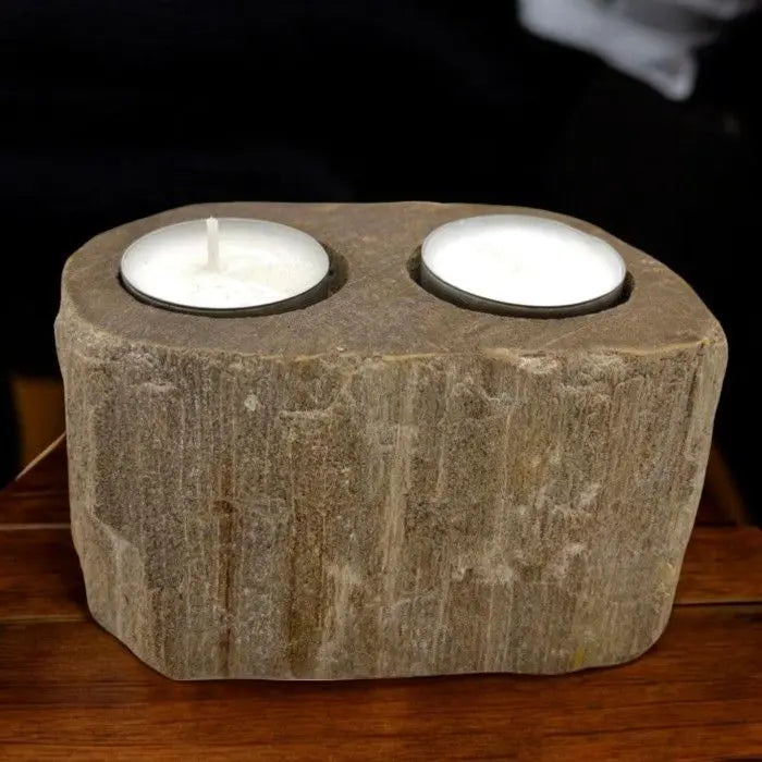 Portavelas doble de madera petrificada color beige con textura rugosa y dos velas blancas sobre superficie de madera.