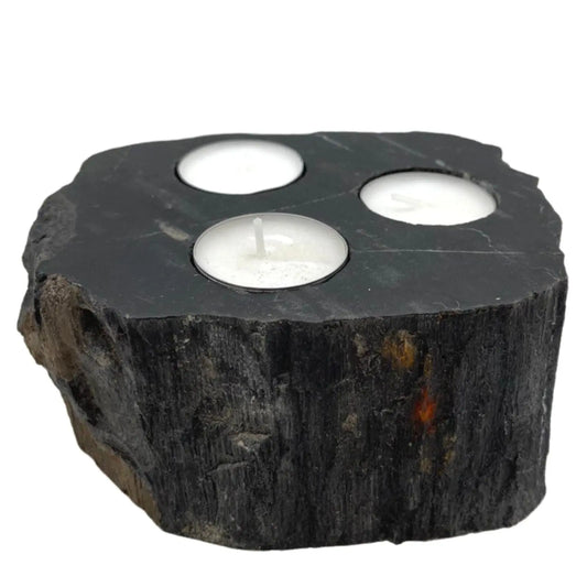 Portavelas triple de madera petrificada negra con textura natural y tres velas tipo tea light blancas.