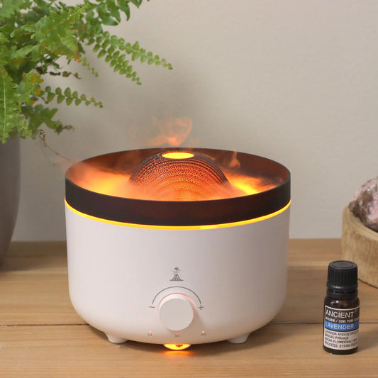Difusor eléctrico Ancient Wisdom, forma cilíndrica blanca con cúpula estilo volcán, luz naranja y vapor tipo erupción.
