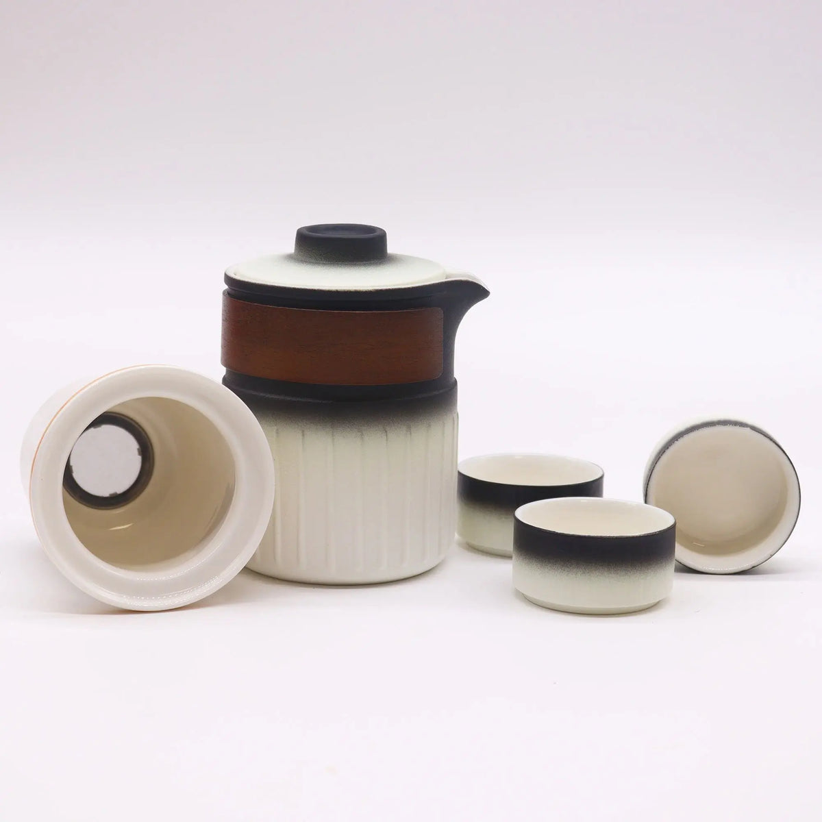 Juego de té en cerámica con tetera, tres tazas y filtro. Diseño bicolor blanco y negro con banda de madera central.