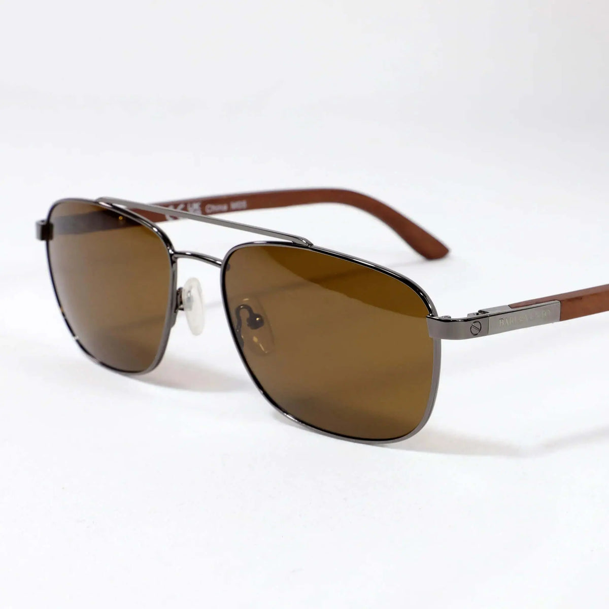 Gafas de sol estilo aviador con montura metálica gris oscuro, lentes café y patillas de madera.