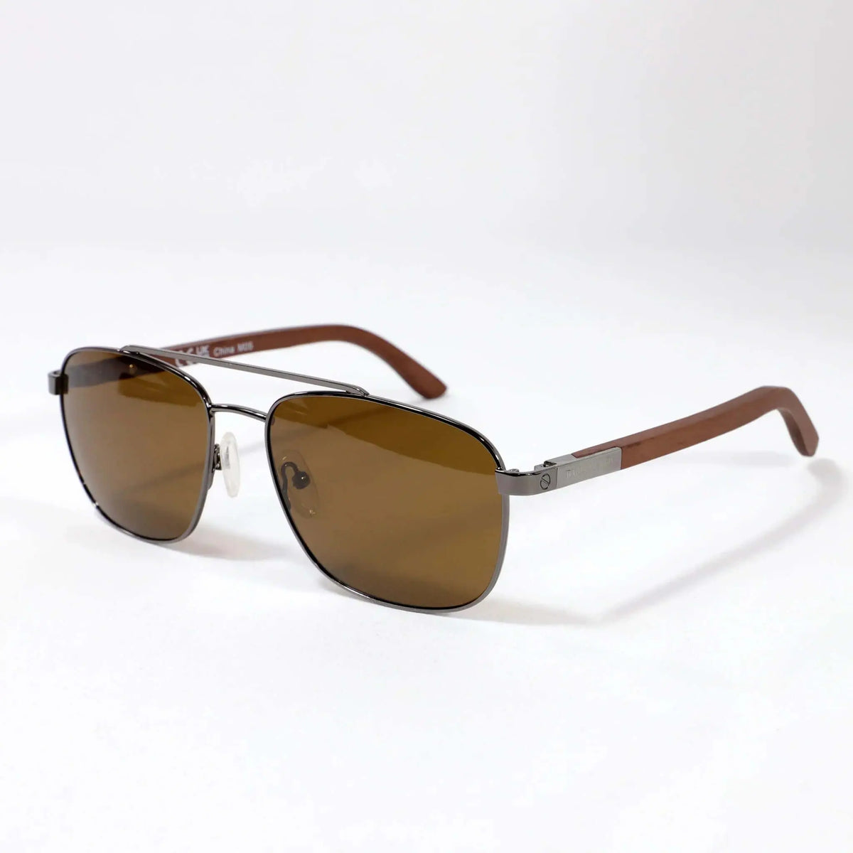Gafas de sol tipo aviador con marco metálico oscuro, lentes marrones y patillas de madera sobre fondo blanco.