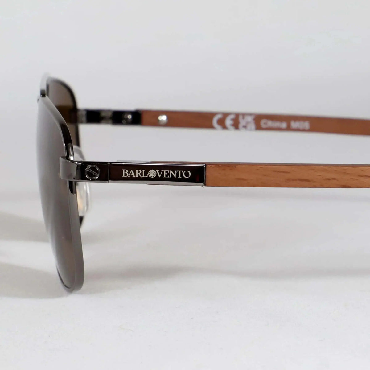 Gafas de sol estilo aviador con montura metálica oscura y patillas de madera clara sobre fondo blanco.