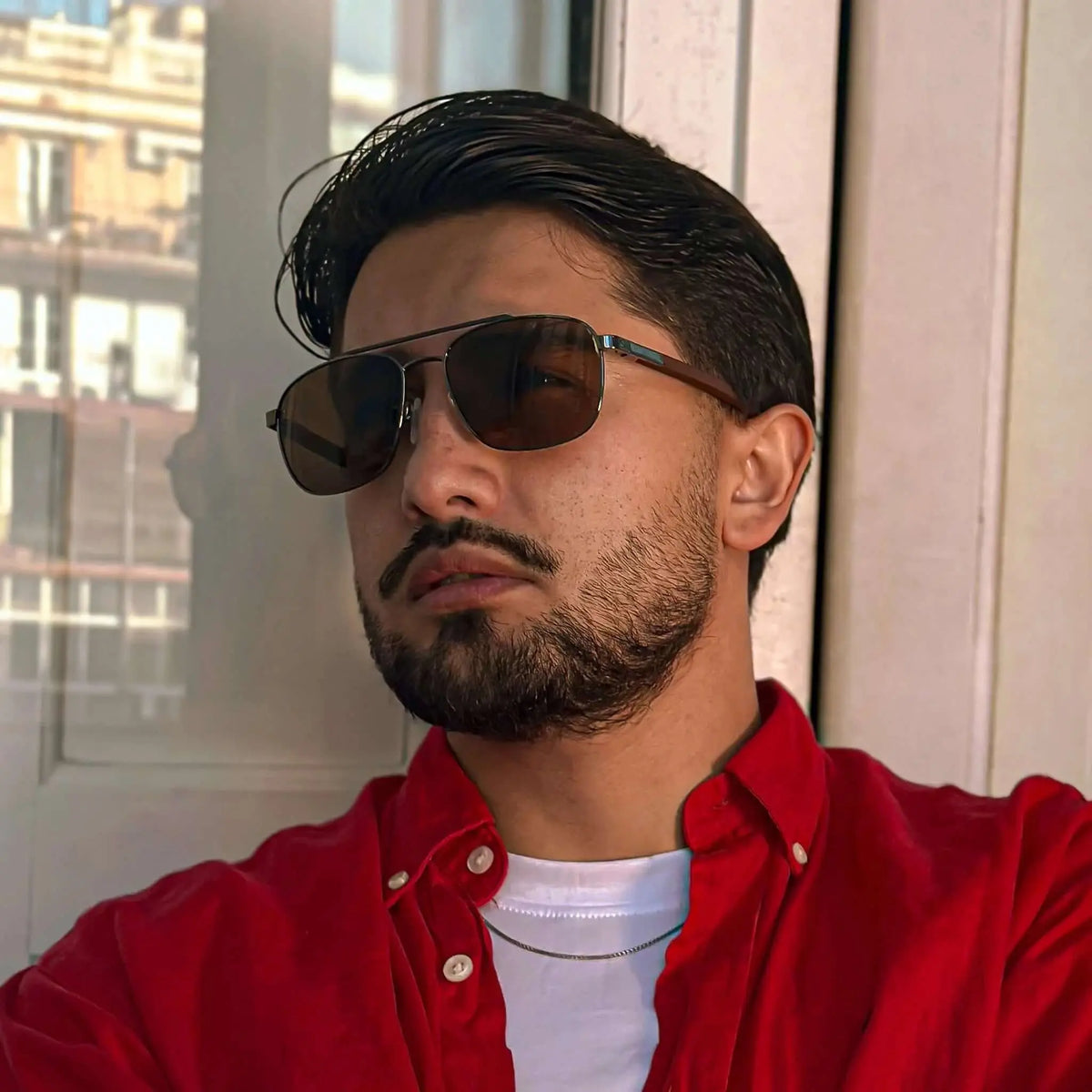 Gafas de sol estilo aviador con montura metálica y patillas de madera, cristales oscuros, puestas por un hombre.