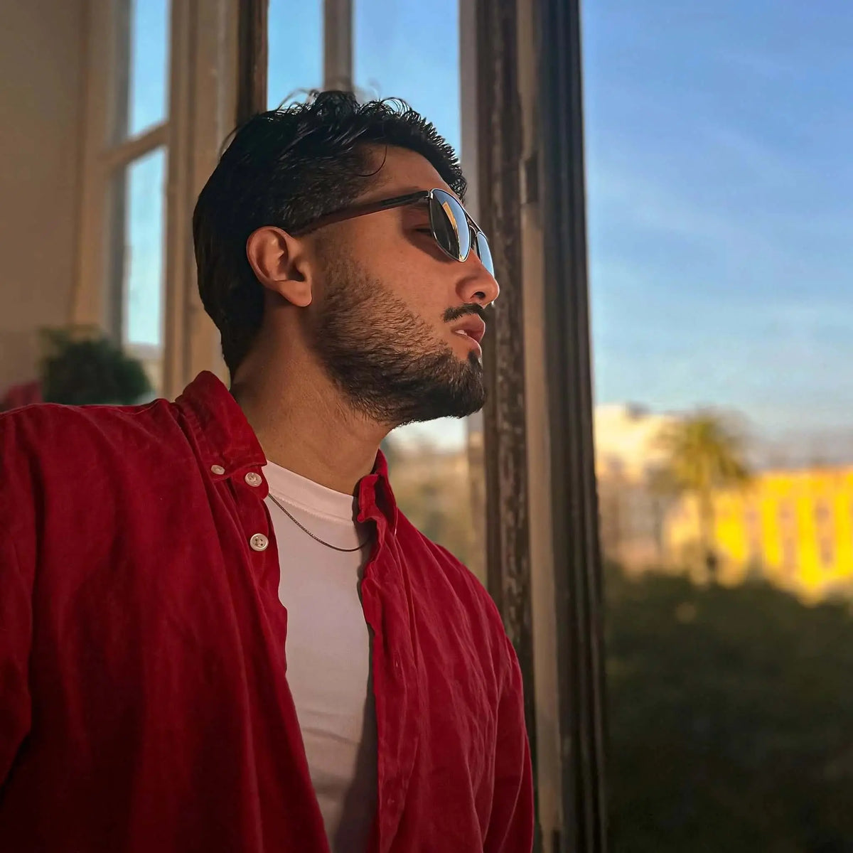 Gafas de sol estilo aviador con montura de madera y lentes oscuras, puestas por un hombre con camisa roja.
