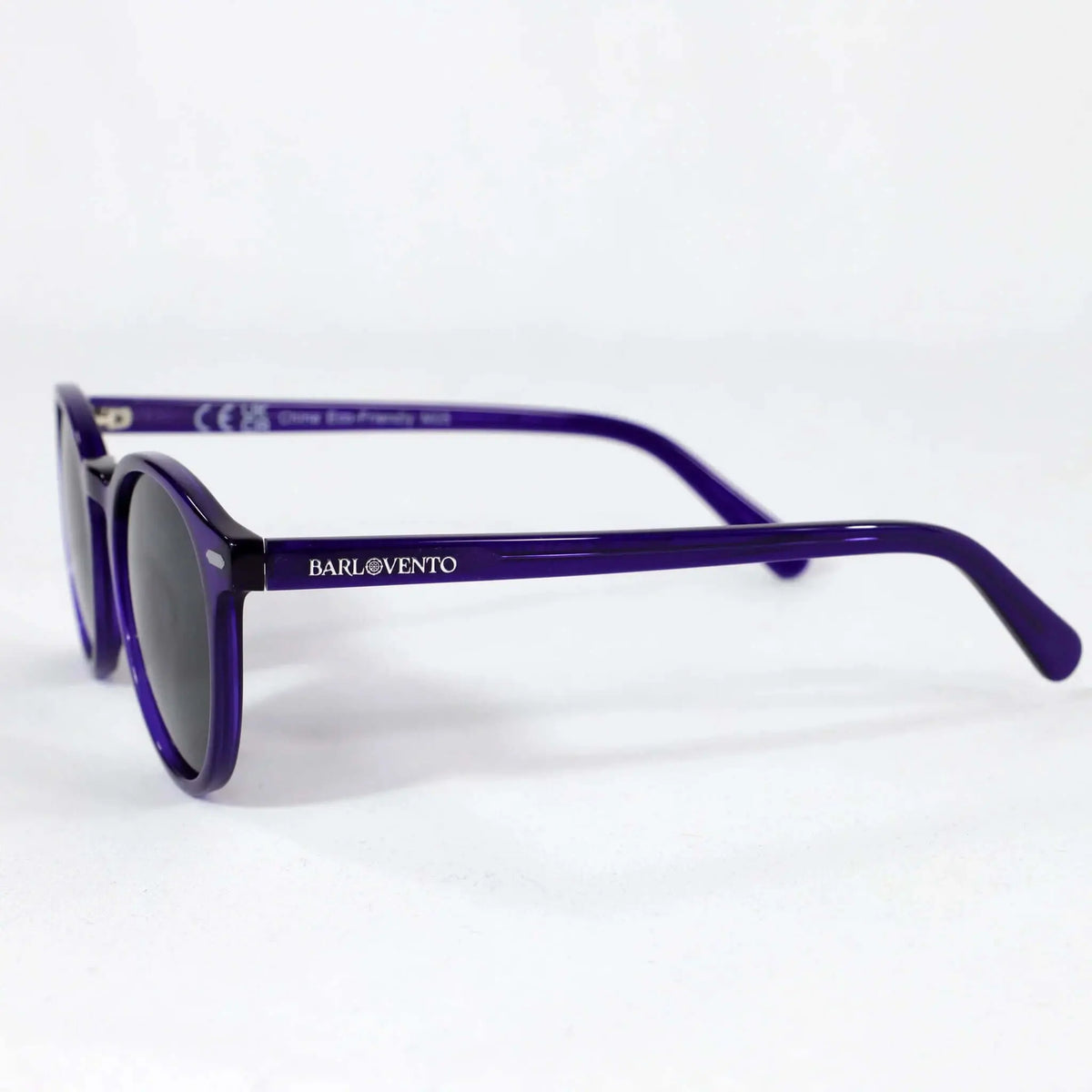 Gafas de sol redondas con montura de plástico en color morado translúcido y cristales oscuros. Diseño clásico.