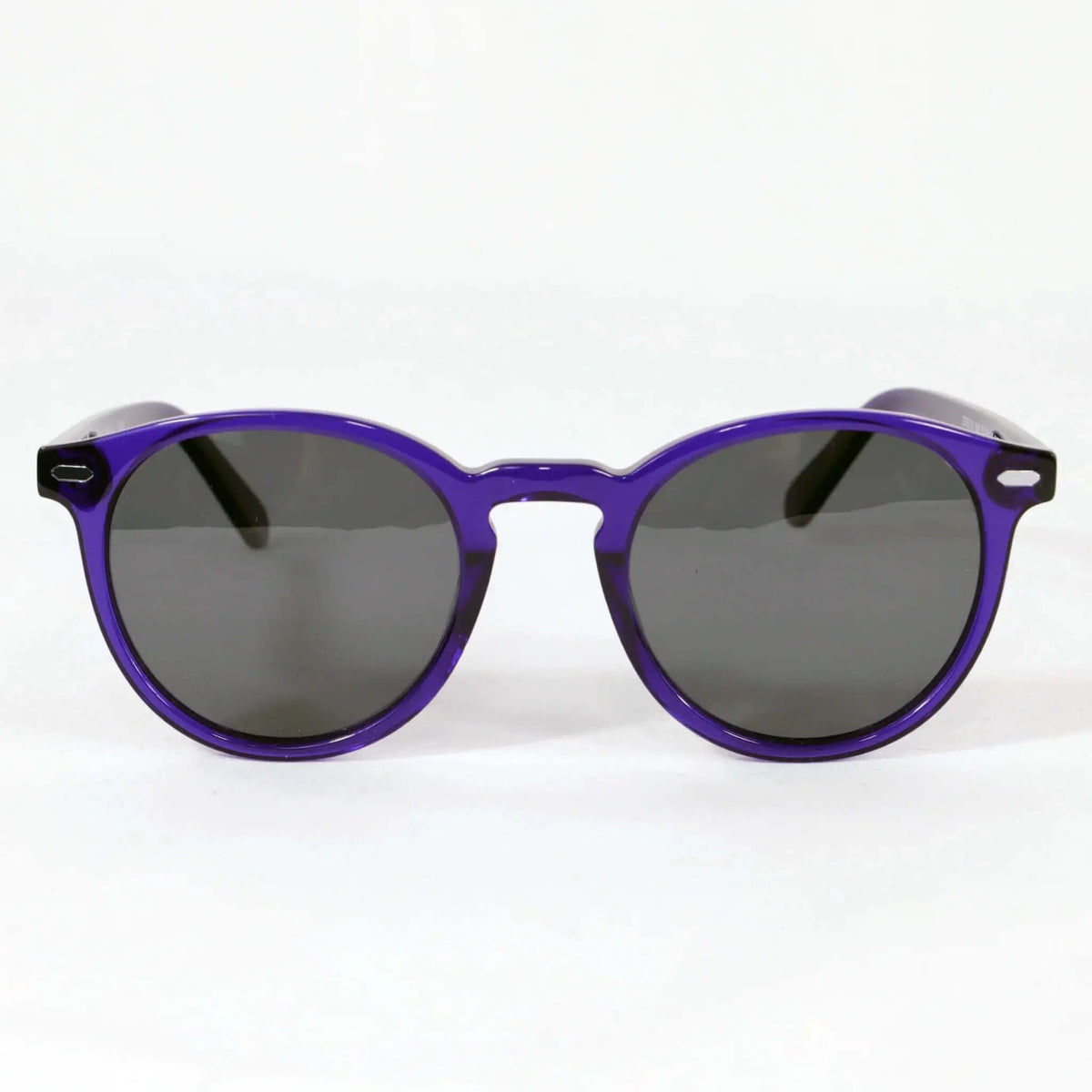 Gafas de sol de estilo redondo con montura de acetato translúcido en color morado y lentes oscuras.