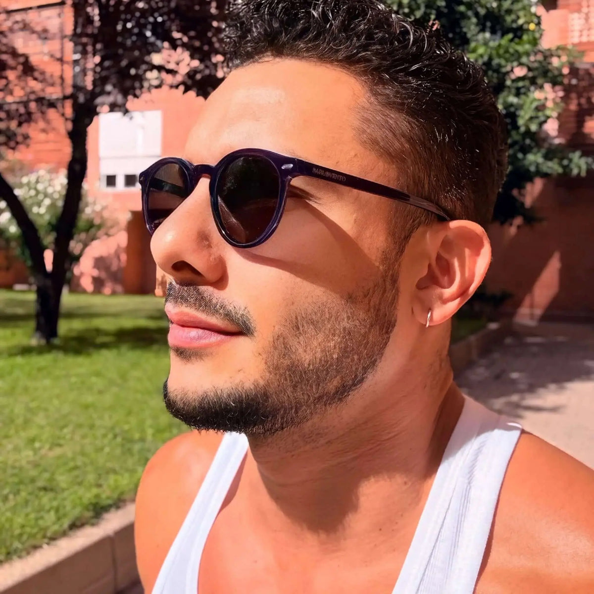 Gafas de sol de montura redonda en color morado oscuro con lentes oscuras, estilo casual y moderno para hombre.
