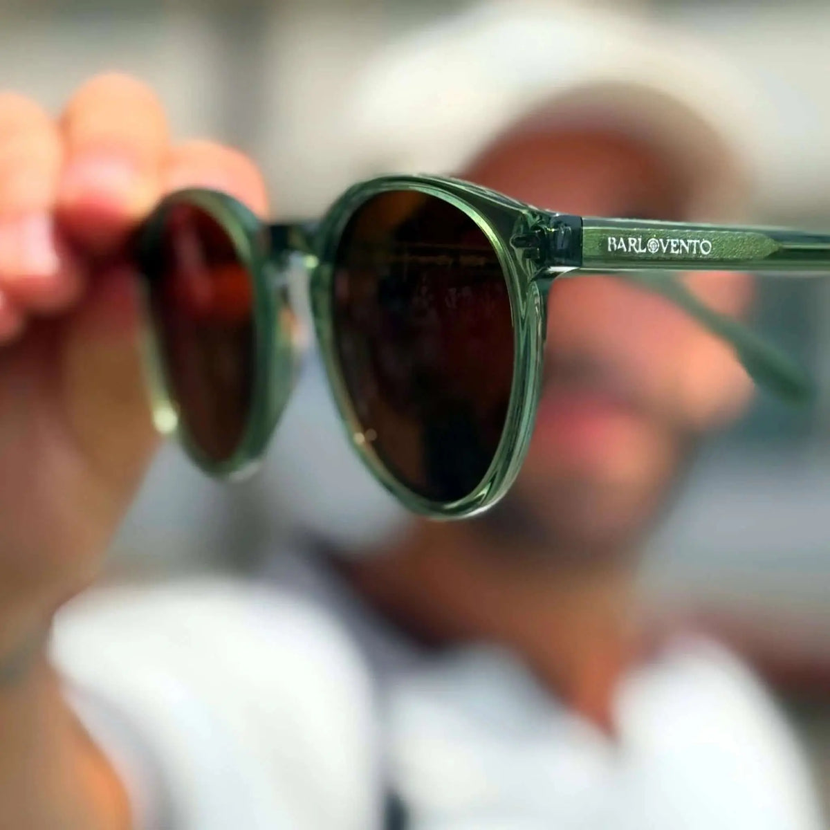 Gafas de sol redondas con montura translúcida color verde oliva y lentes oscuras de tono marrón.