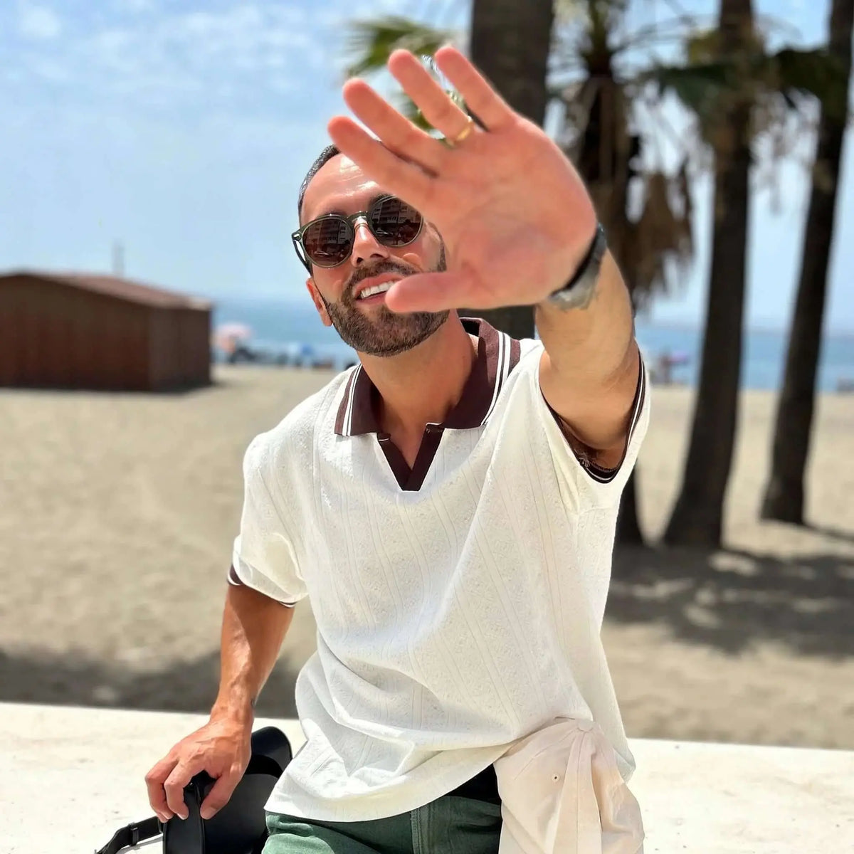 Gafas de sol redondas con montura de carey verde y lentes marrones, estilo clásico y casual en un entorno de playa.