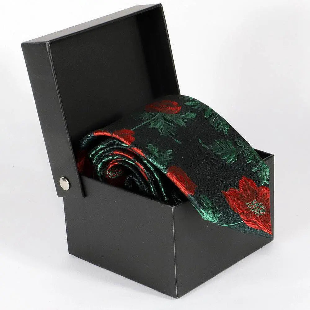 Corbata negra con estampado floral de flores rojas y tallos verdes en una caja de regalo negra abierta.