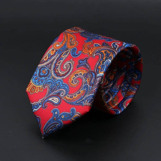 Corbata roja de seda con estampado paisley en tonos azules y naranjas, diseño clásico enrollado sobre fondo oscuro.