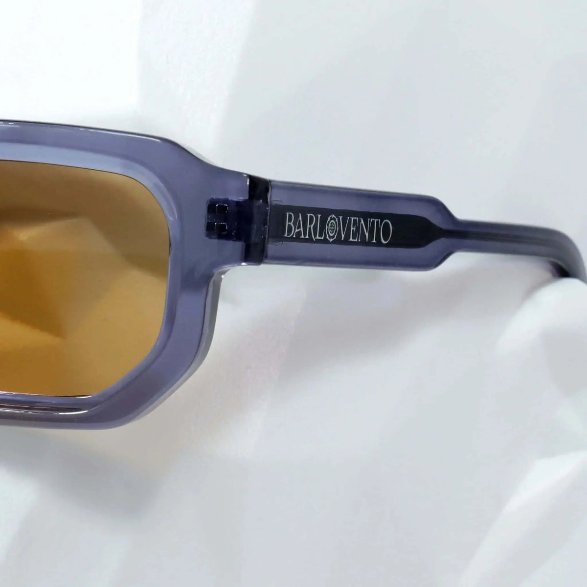 Gafas de sol de montura rectangular color azul traslúcido y lentes en tono ámbar. Diseño moderno con patillas gruesas.