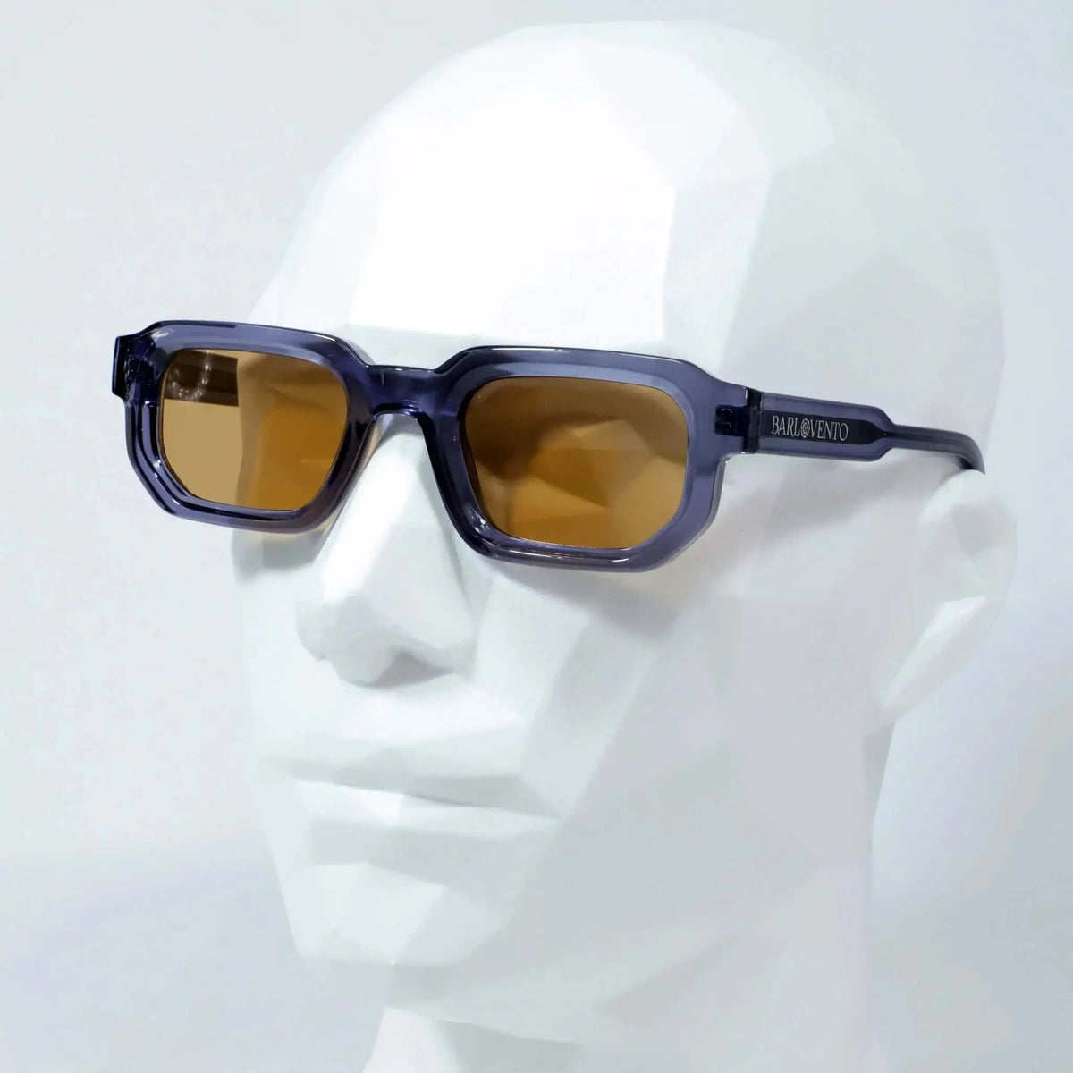 Gafas de sol rectangulares con montura azul translúcida y lentes marrones sobre un maniquí. Diseño moderno y minimalista.