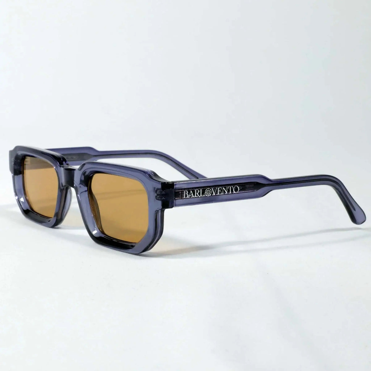 Gafas de sol de montura cuadrada en acetato traslúcido azul y cristales marrones de estilo retro sobre fondo blanco.