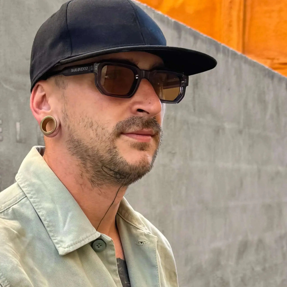 Gafas de sol de montura azul cuadrada y lentes marrones oscuras, estilo moderno y urbano sobre un hombre con gorra.