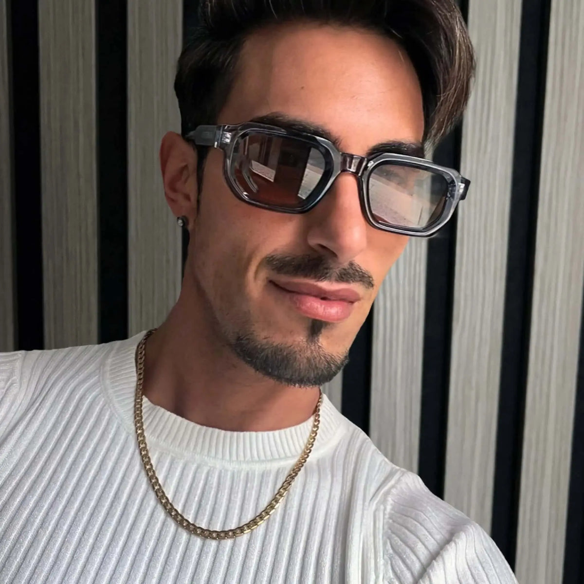 Gafas de sol de montura cuadrada translúcida gris azulada con cristales marrones y estilo moderno.