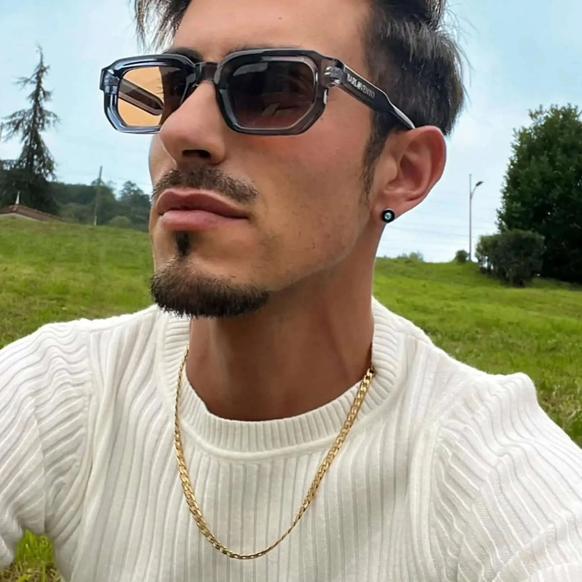 Gafas de sol de montura rectangular transparente en tono azulado con cristales marrones oscuros. Estilo moderno.