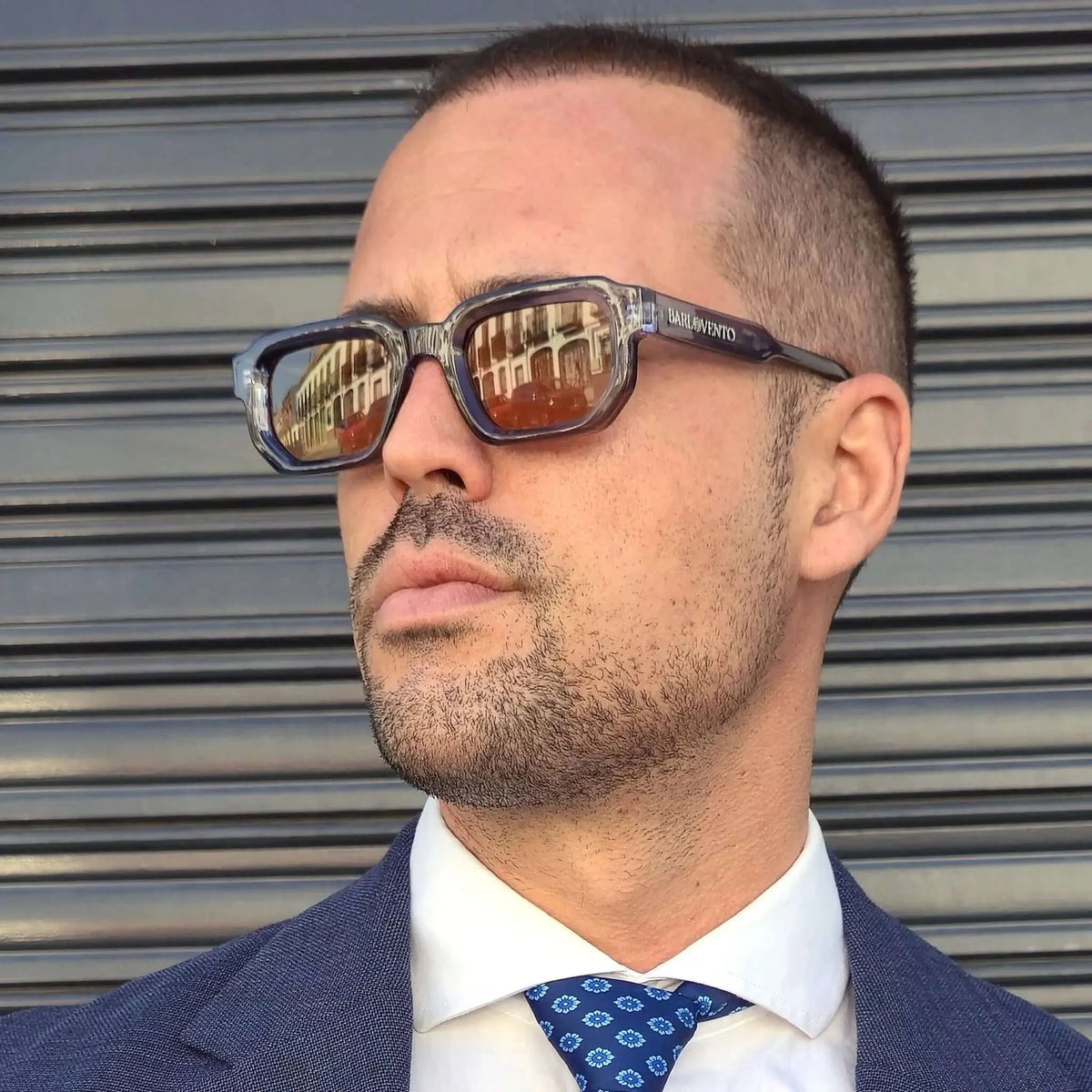 Gafas de sol rectangulares con montura azul traslúcida y lentes marrones reflectantes puestas en un hombre.