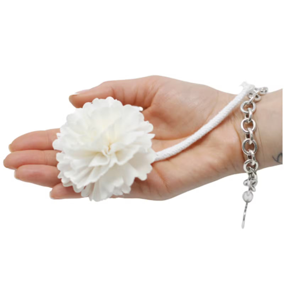 Mano sosteniendo una flor difusora blanca con cuerda de algodón blanca sobre fondo blanco.