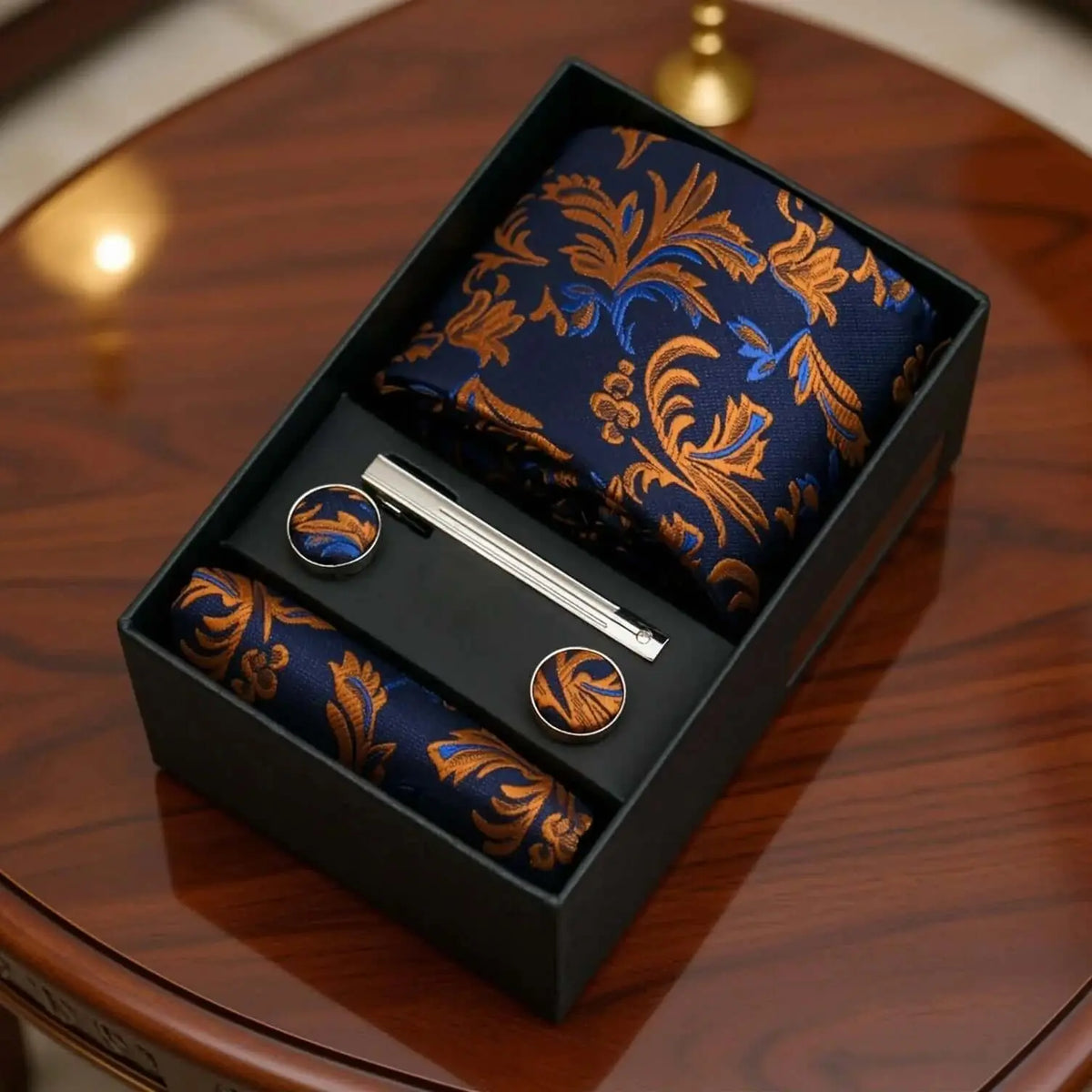 Set de regalo: corbata y pañuelo azul con estampado paisley naranja, gemelos y pasador plateado en caja negra.