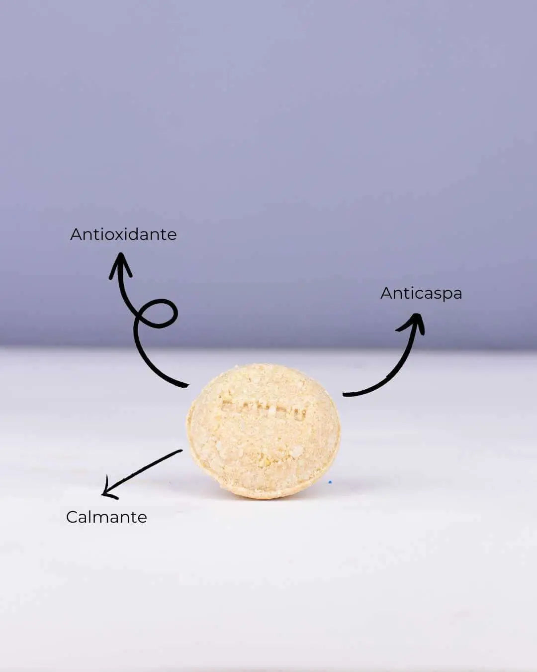 Champú sólido circular Banbu, beige y texturizado, sobre fondo lila, con flechas indicando beneficios clave.
