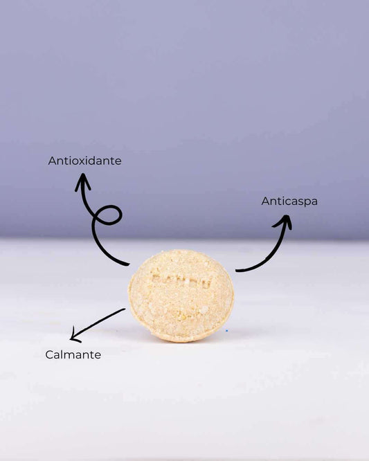 Champú sólido circular Banbu, beige y texturizado, sobre fondo lila, con flechas indicando beneficios clave.