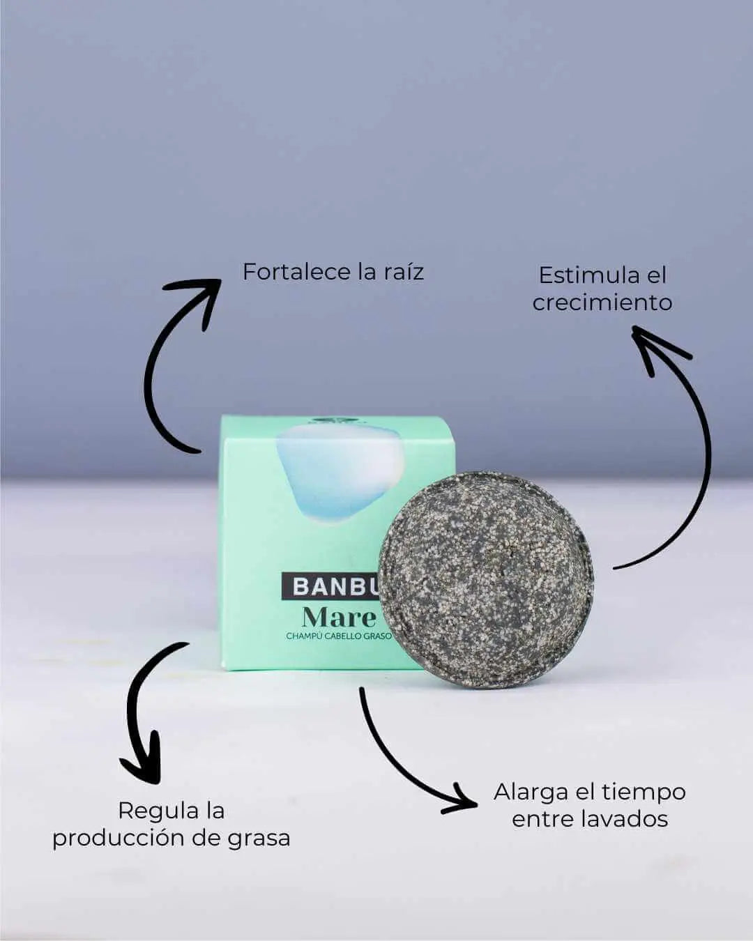 Champú sólido gris texturizado Banbu Mare junto a su caja verde menta, con flechas indicando sus beneficios.
