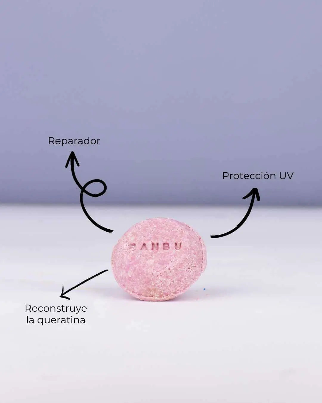 Champú sólido rosa BANBU sobre fondo claro, señalando sus beneficios reparadores, protección UV y queratina.