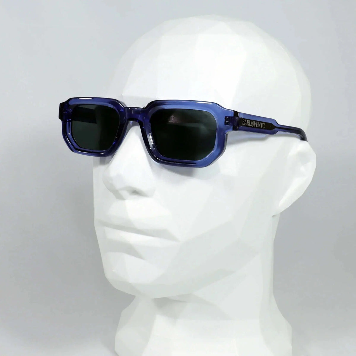 Gafas de sol rectangulares con montura de acetato azul traslúcido y lentes oscuras, sobre maniquí blanco.