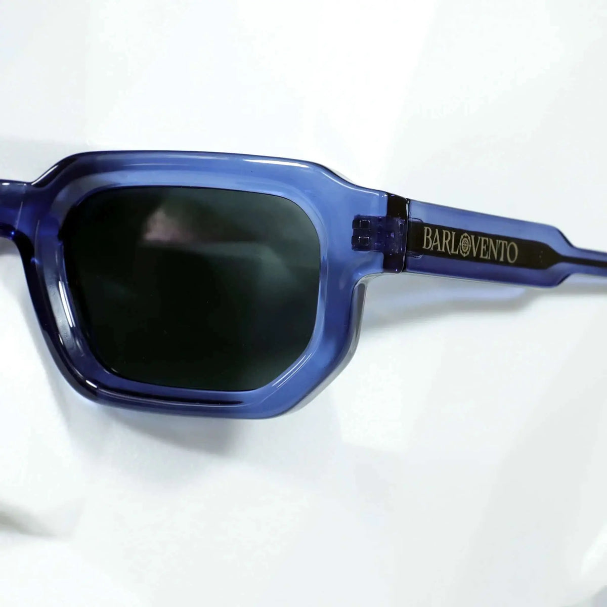 Gafas de sol rectangulares en acetato azul traslúcido con lentes negras oscuras y diseño moderno.
